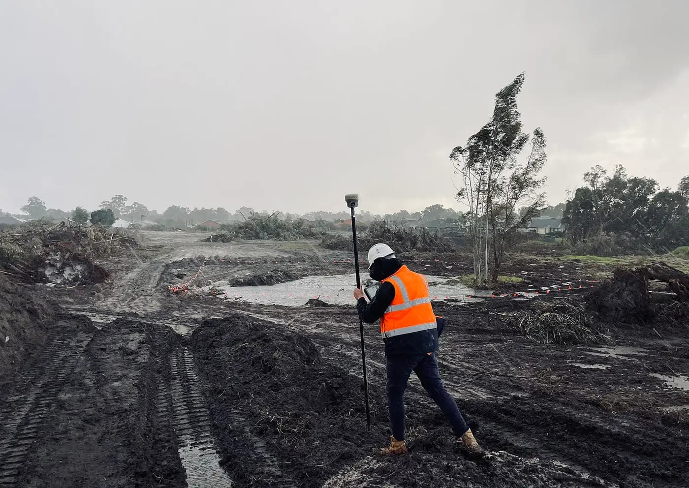 Surveyor holding a GNSS rover pole on a construction site