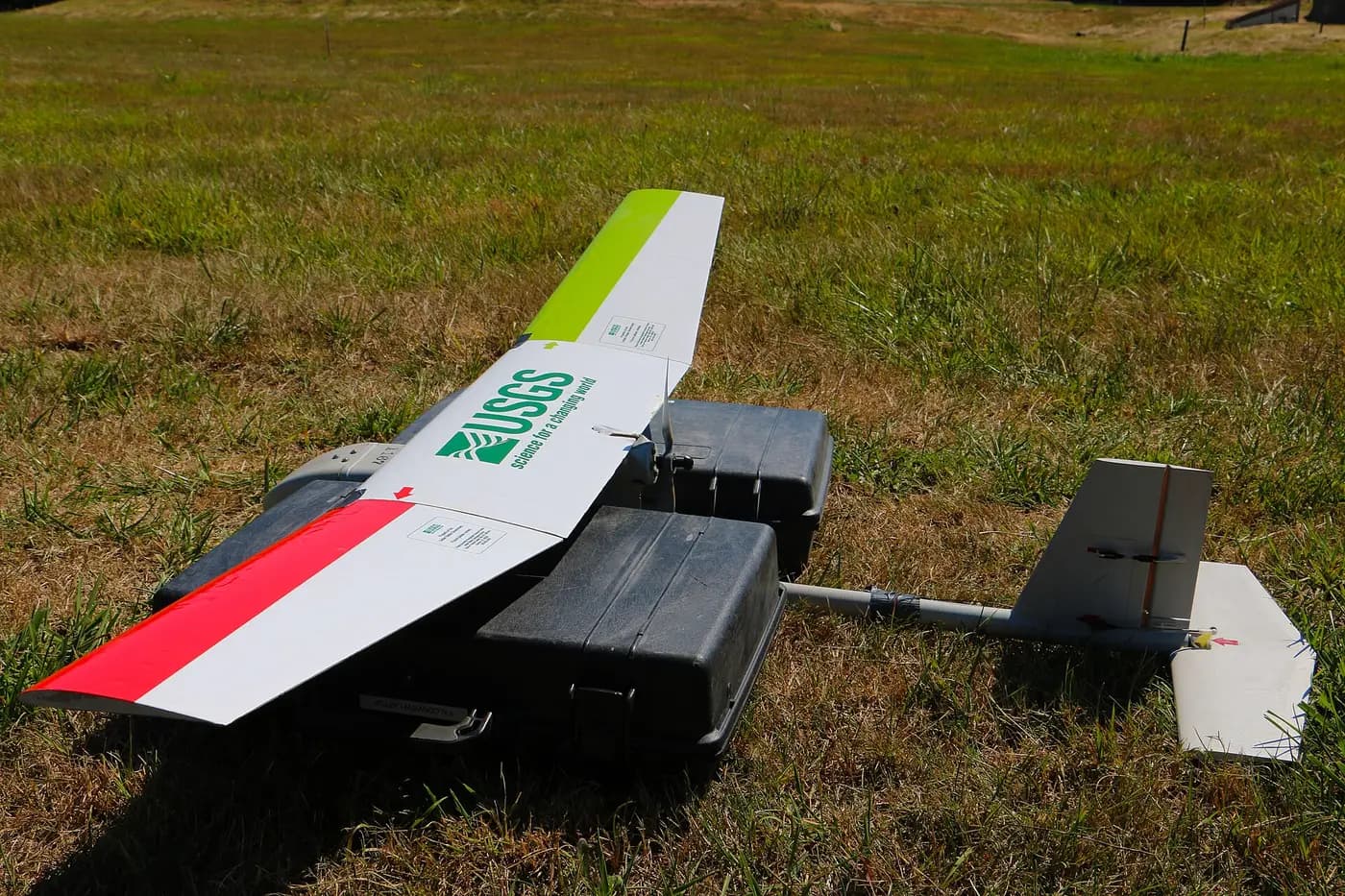 USGS fixed-wing survey drone resting on its cases in a field